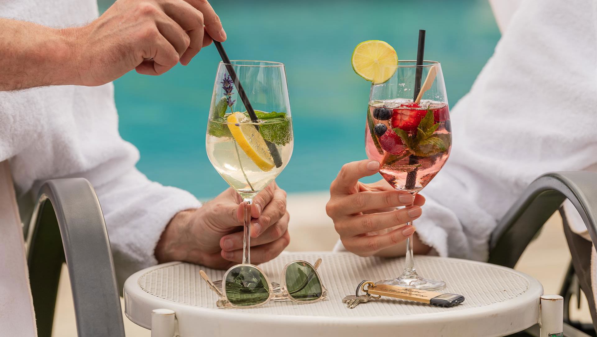 Due persone prendono un cocktail a bordo della piscina esterna
